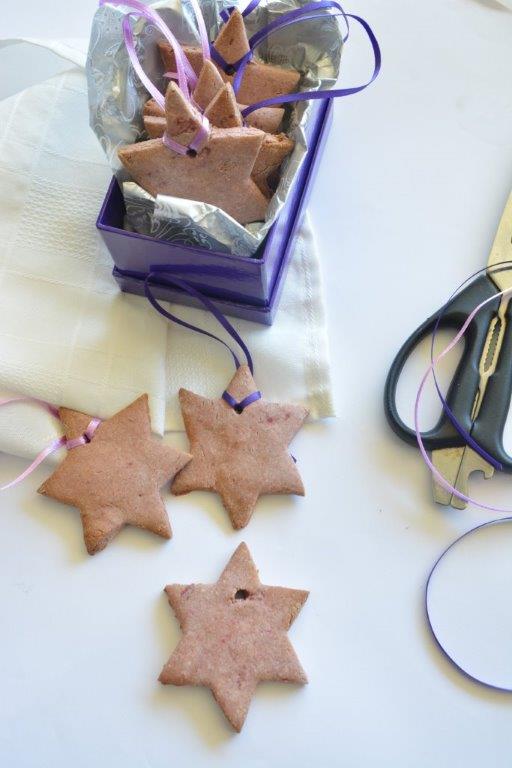 Gluten-free star-shaped Christmas cookies with ribbon, scissors and a purple gift box