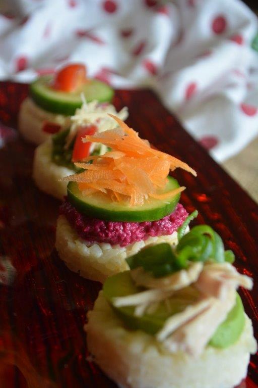 Gluten-free rice round canapes with various savoury toppings on a red plate