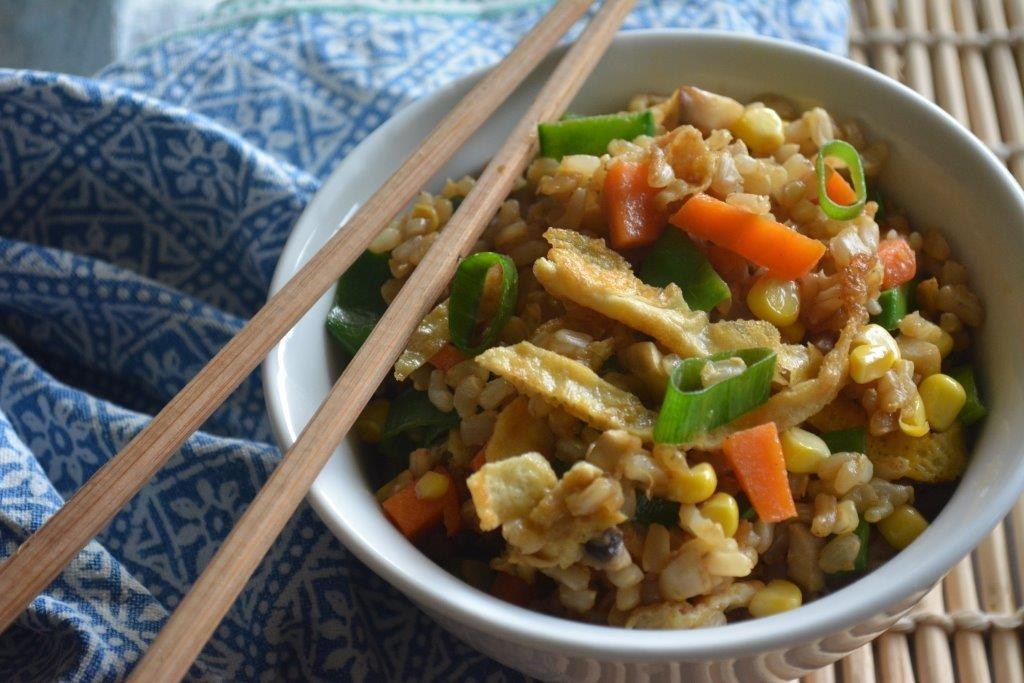 Bowl of gluten-free fried rice with chopsticks  on bamboo board with blue patterned tea towel. Top 10 gluten-free lunch recipes