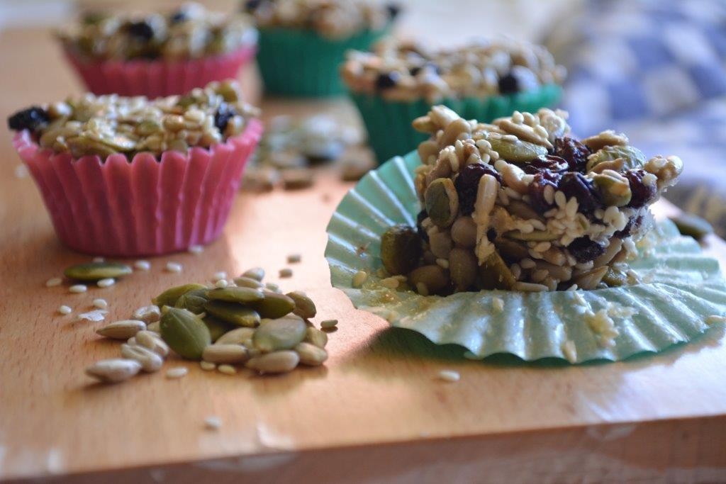 Gluten-free seed clusters in coloured paper wrappers on a wooden board