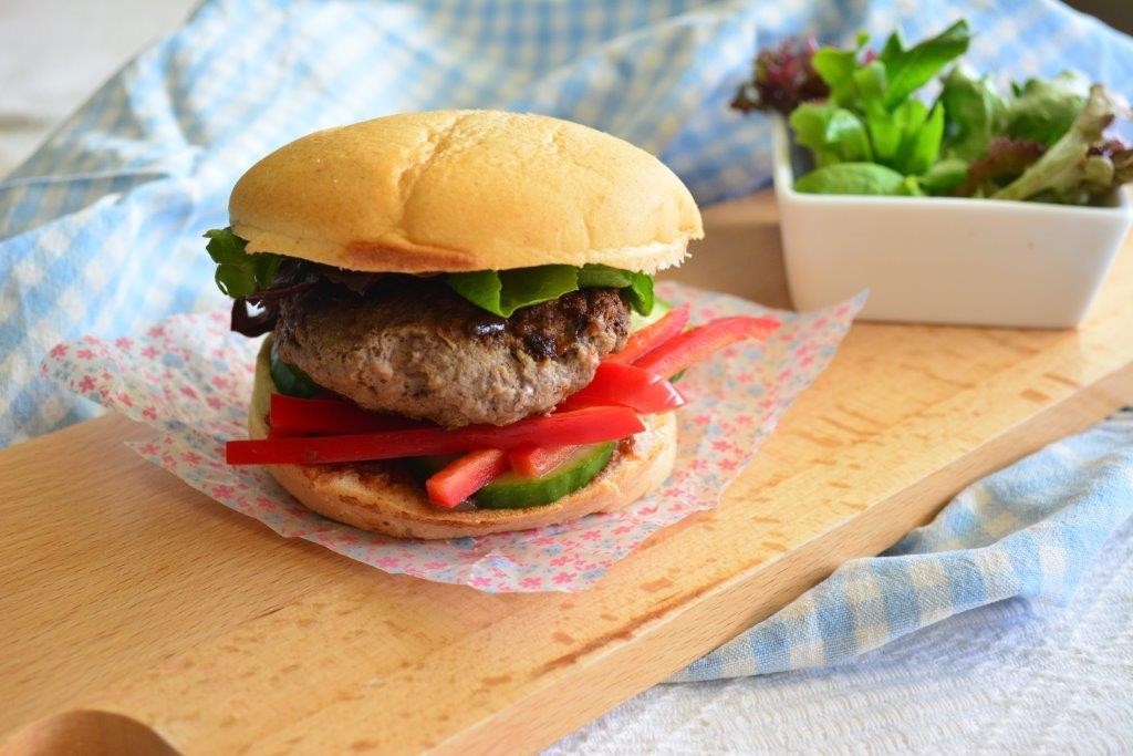 Gluten-free hamburger with red capsicum and lettuce in the background, representing GFL's top 5 fast-food inspired lunchtime recipes