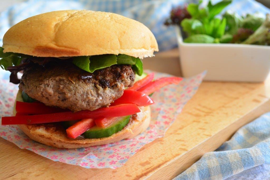 Gluten-free hamburger in bun with red capsicum, lettuce and cucumber