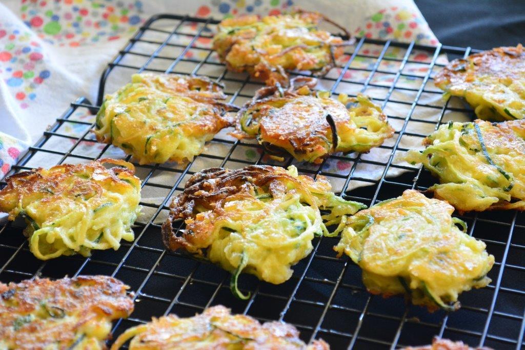 Gluten-free zoodle fritters on a wire cooling rack with a tea towl in the background