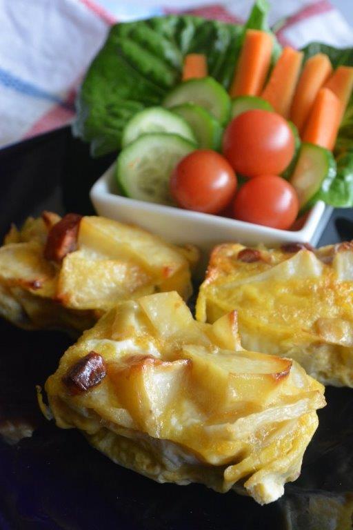 Spanish potato tortilla bites with cherry tomatoes, cucumber, lettus and carrot sticks in background