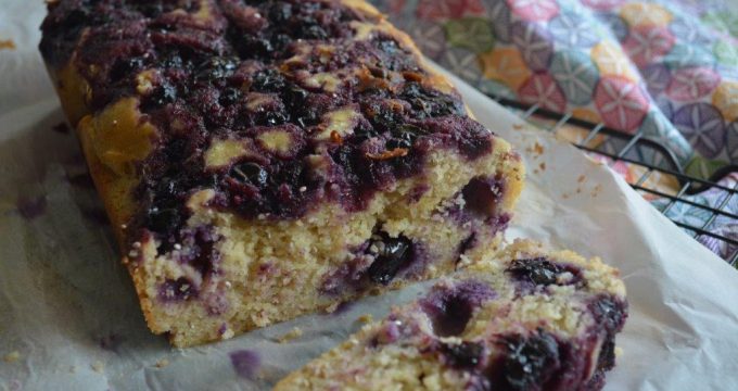Gluten-free lemon and blueberry breakfast loaf with coloured cloth in background