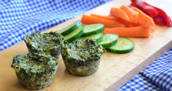 Gluten-free spinach and feta bites on a board with cucumber, carrot sticks and red capsicum